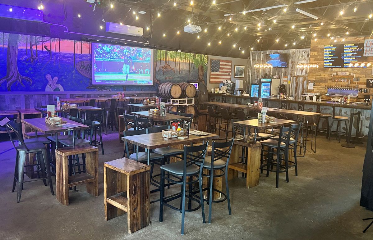 The real Bullfrog Creek taproom, with wood tables, string lights and the bar